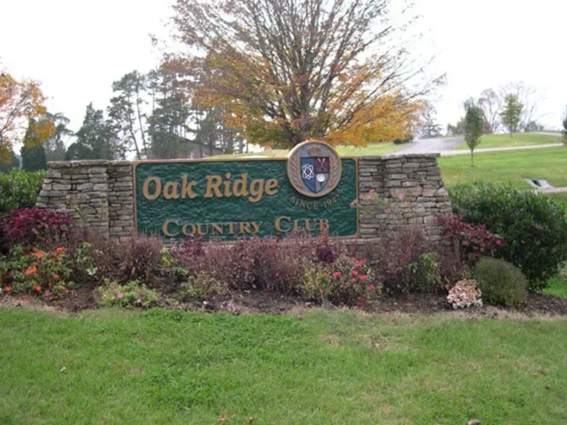 Oak Ridge Country Club sign with stone structure, green lawn, bushes, and fall foliage.