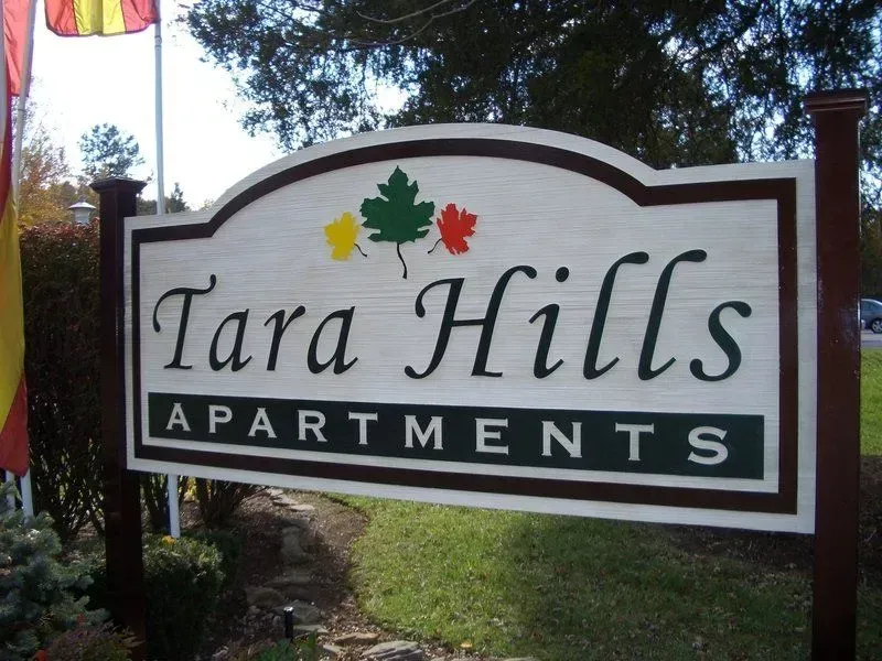 Tara Hills Apartments sign with stylized leaves. Brown, white, green, and gold colors.