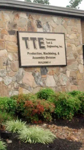 Sign for Tennessee Tool & Engineering, Inc. on a stone building with landscaping.
