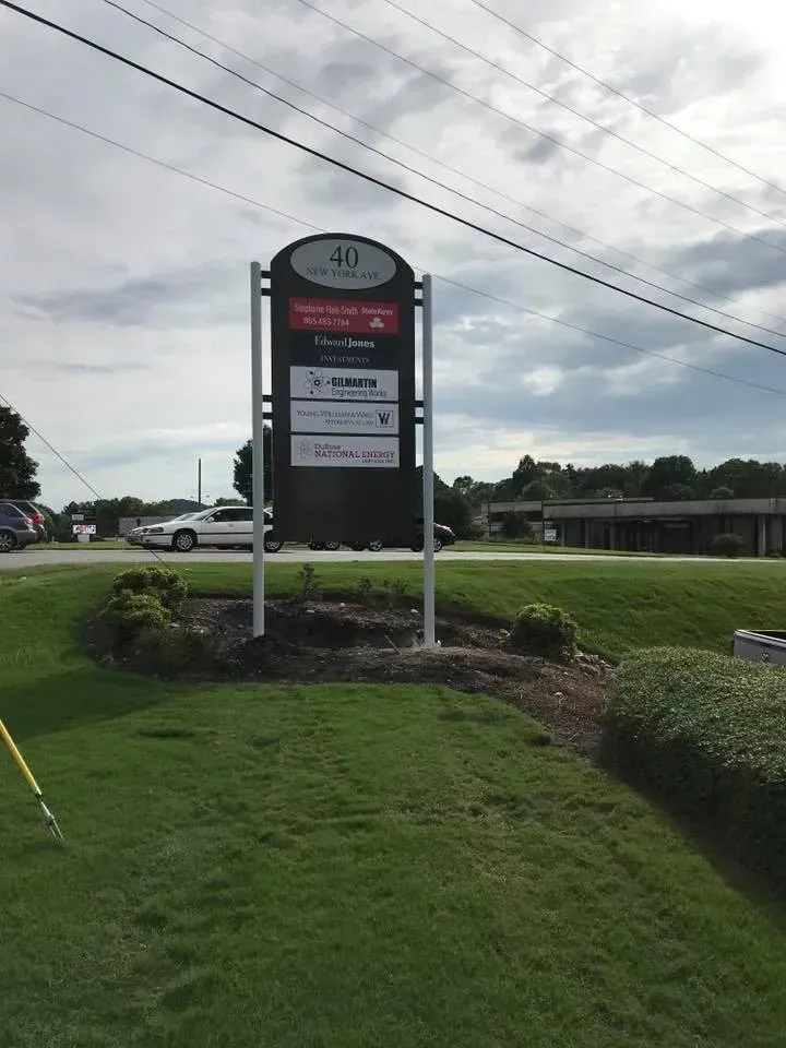 Sign for businesses at a commercial location. Rectangular sign with multiple logos on a grassy area.