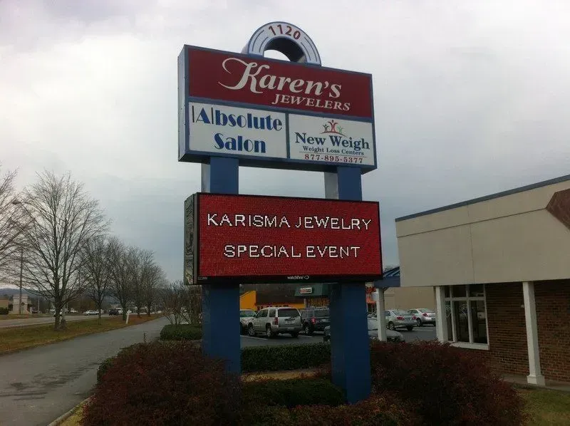 Sign with business names: Karen's Jewelers, Absolute Salon, New Weigh, and Karisma Jewelry.  Outside, cloudy day.