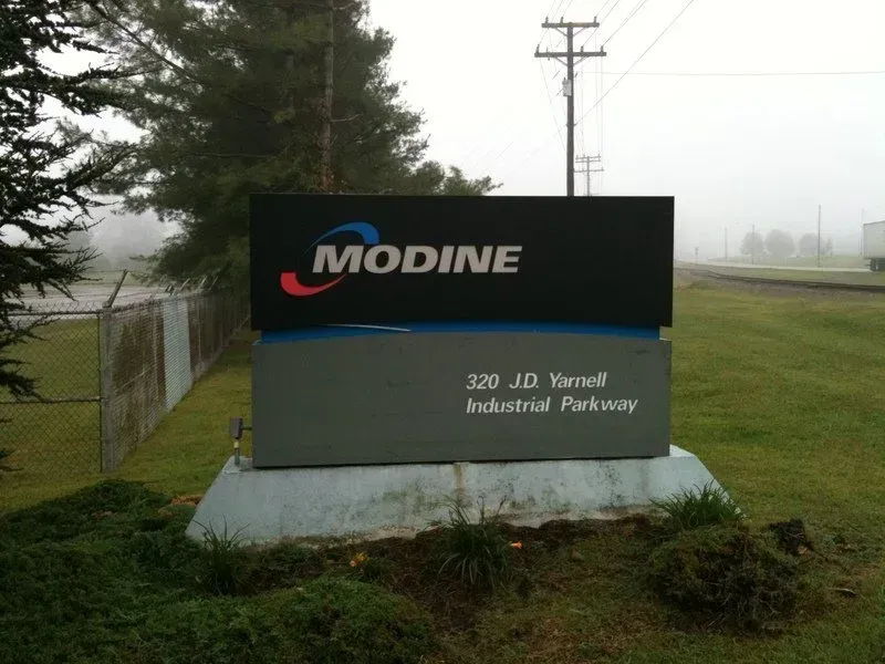 Modine sign at 320 J.D. Yarnell Industrial Parkway; black and gray with logo; outdoor, foggy setting.
