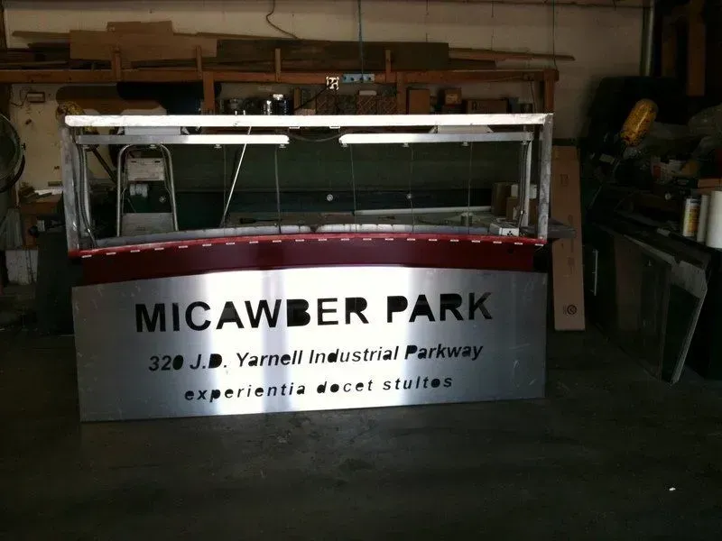 Sign for Micawber Park with address, illuminated display case, metal construction.
