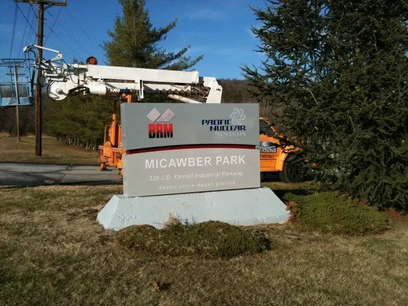 Sign for Micawber Park with an orange truck and lift in the background.