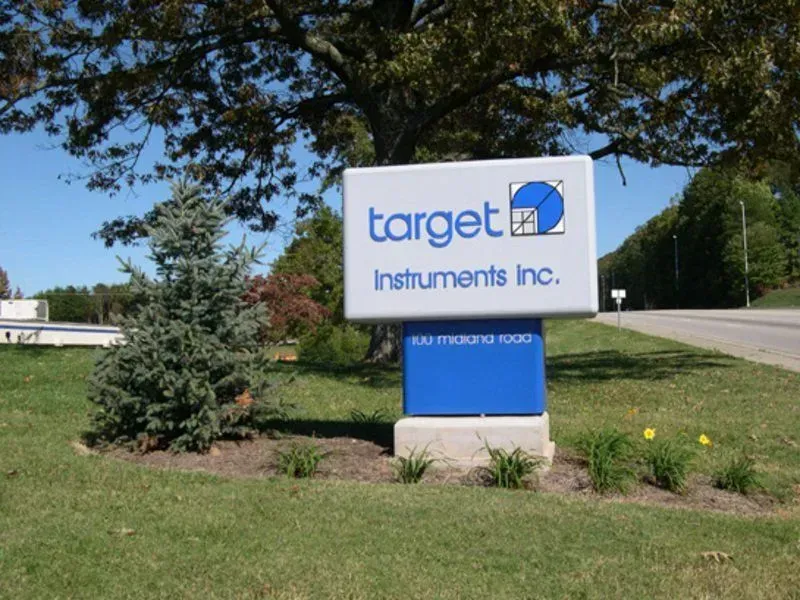Sign for Target Instruments Inc. with logo and address, located outdoors. Blue, white, and gray colors.