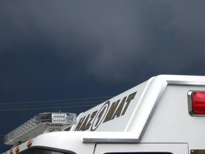 White hazmat truck with dark storm clouds overhead.