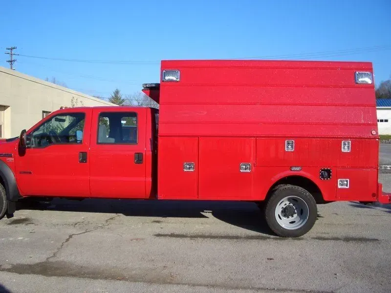 Red work truck with a utility body, parked outdoors.