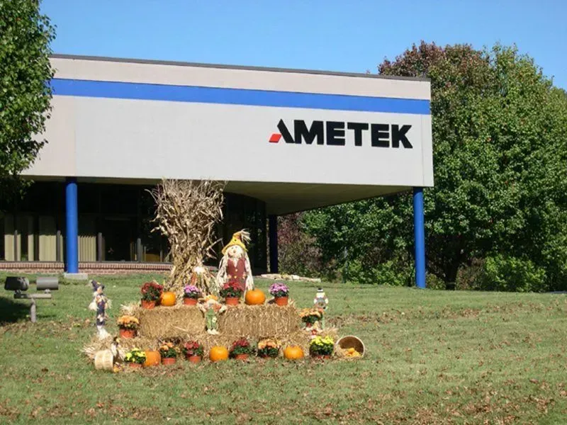AMETEK building with fall decorations: pumpkins, hay bales, and a scarecrow.