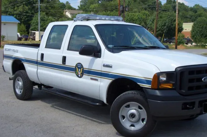 White and blue law enforcement truck with flashing lights, parked. 