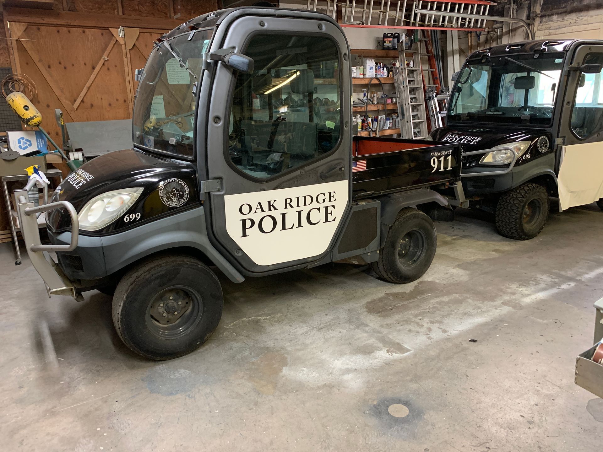 Two Oak Ridge Police vehicles parked inside a garage. One is black and gray, labeled 