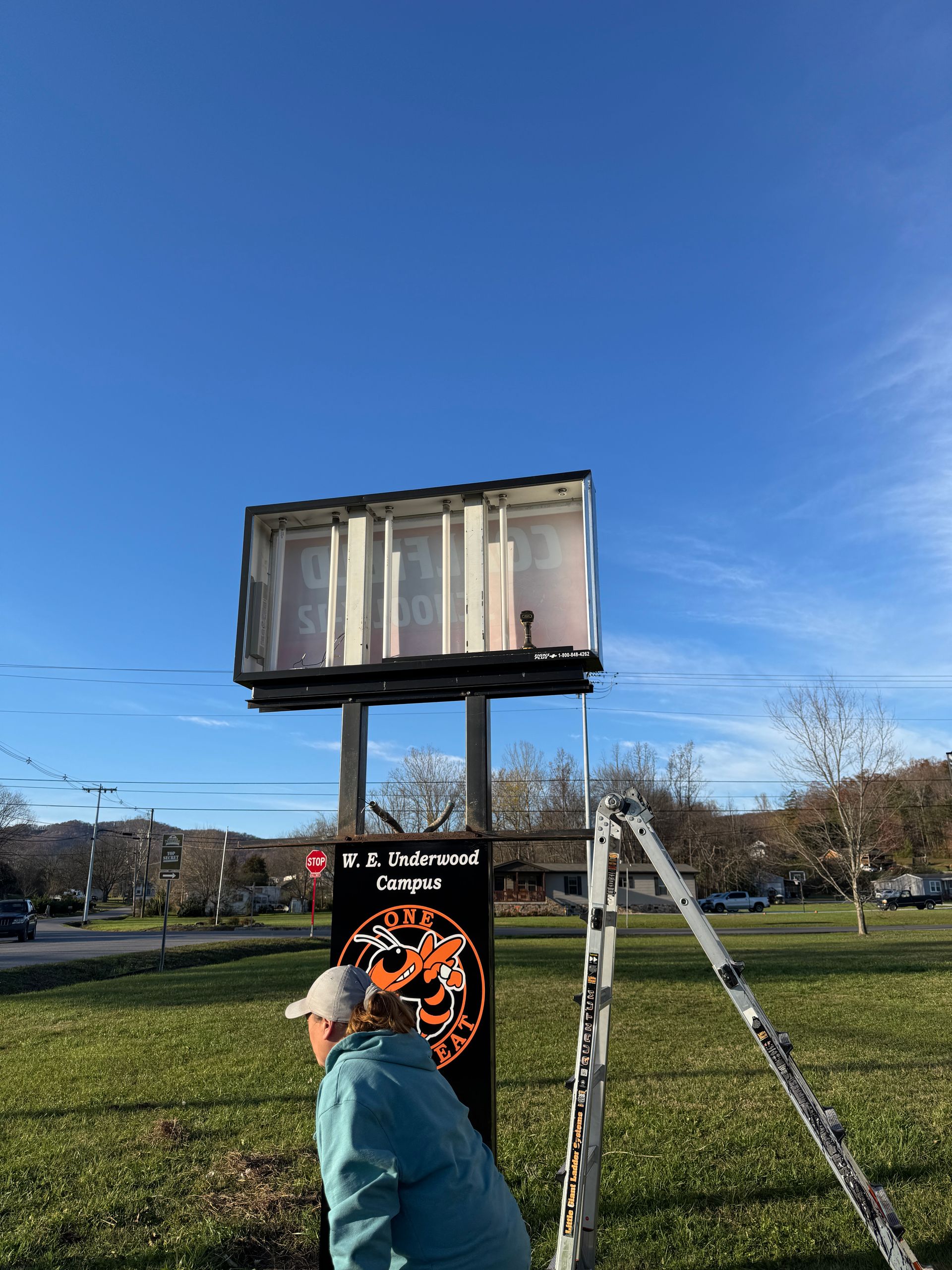 Sign for T.S. Underwood Repair, with woman, ladder, and blue sky.