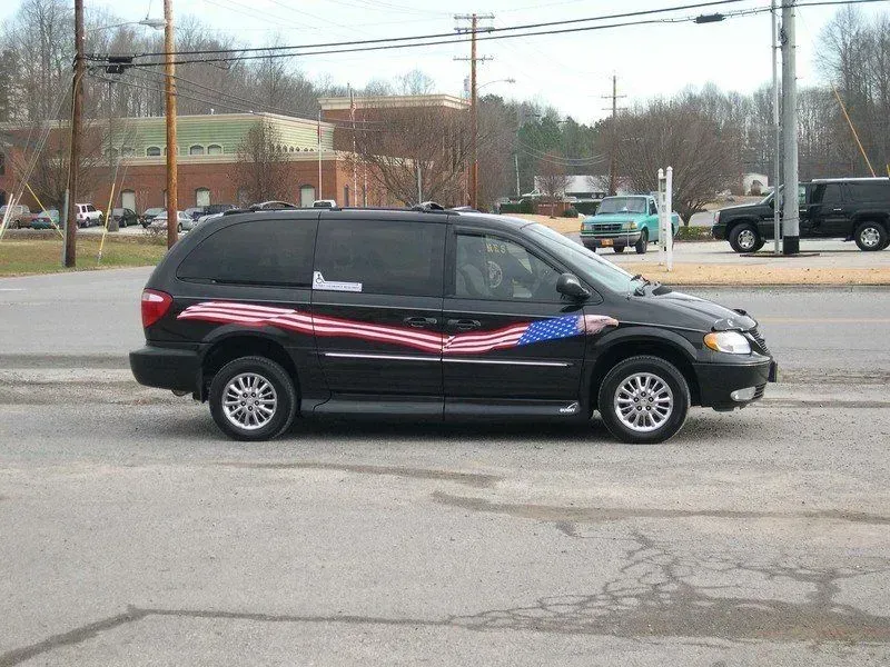 Black minivan with American flag-themed decal on the side, parked on asphalt.