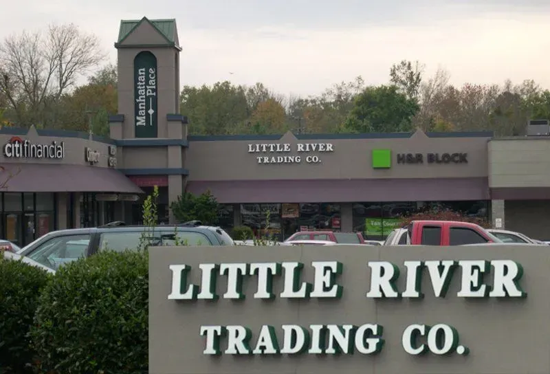 Little River Trading Co. storefront with sign; other businesses visible. Cloudy day.