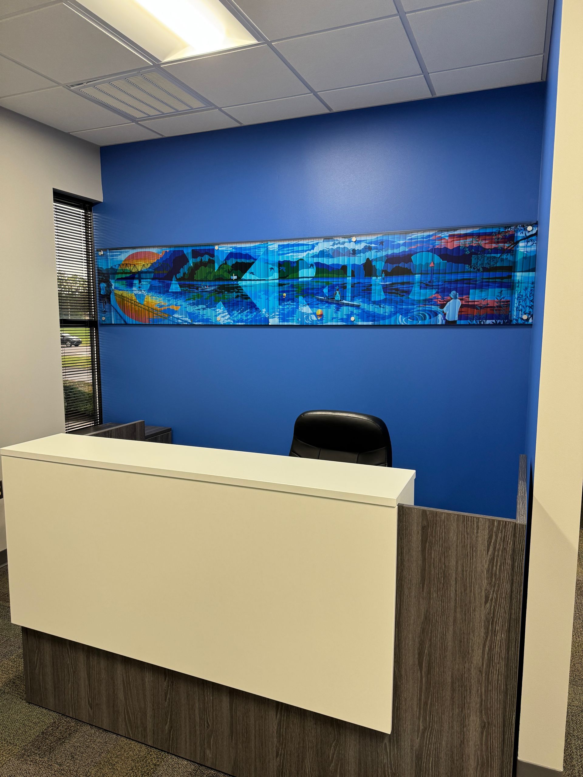 Reception area with a white counter and blue wall featuring artwork.