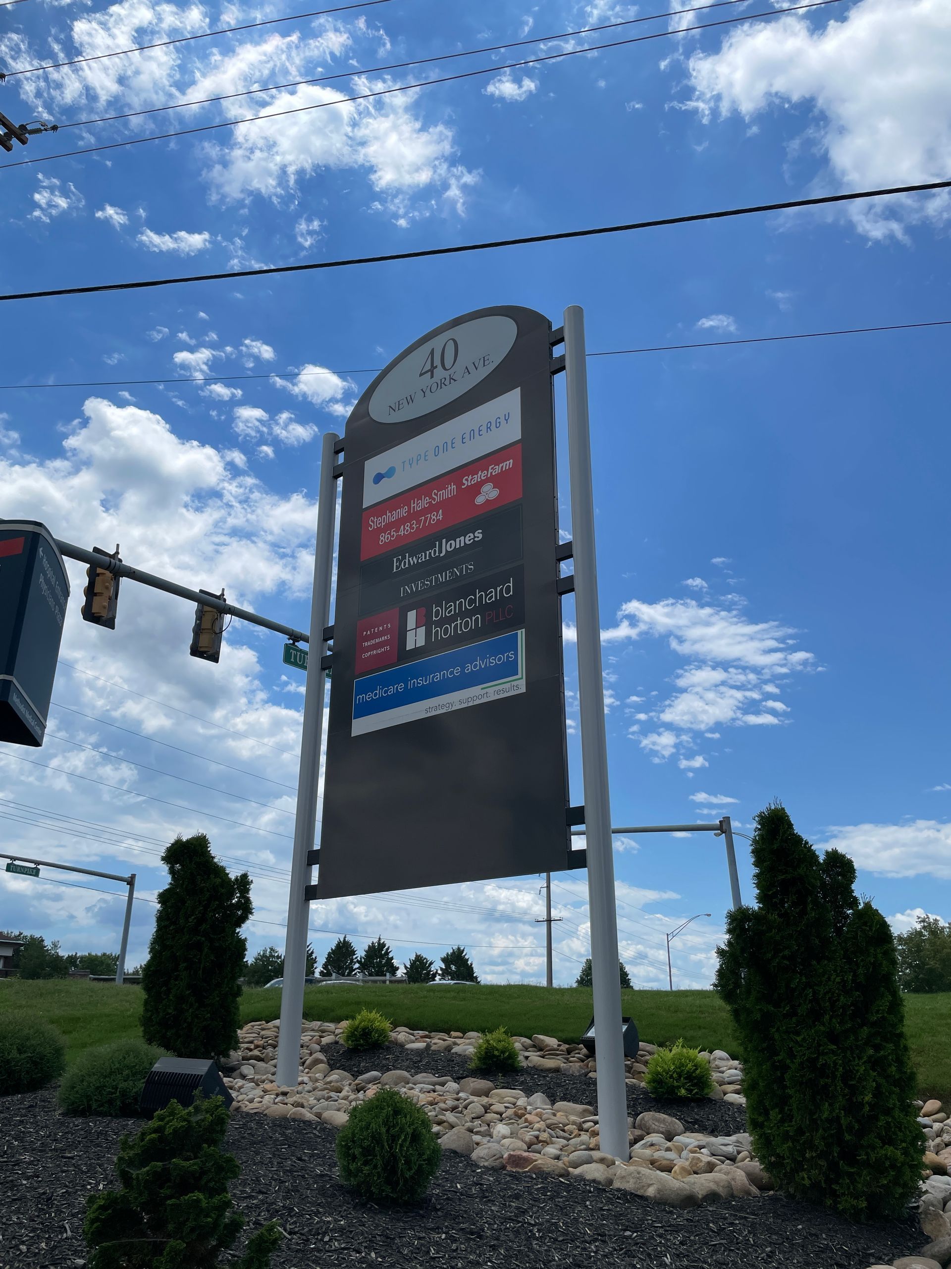 Signpost with store names against a blue sky with clouds.