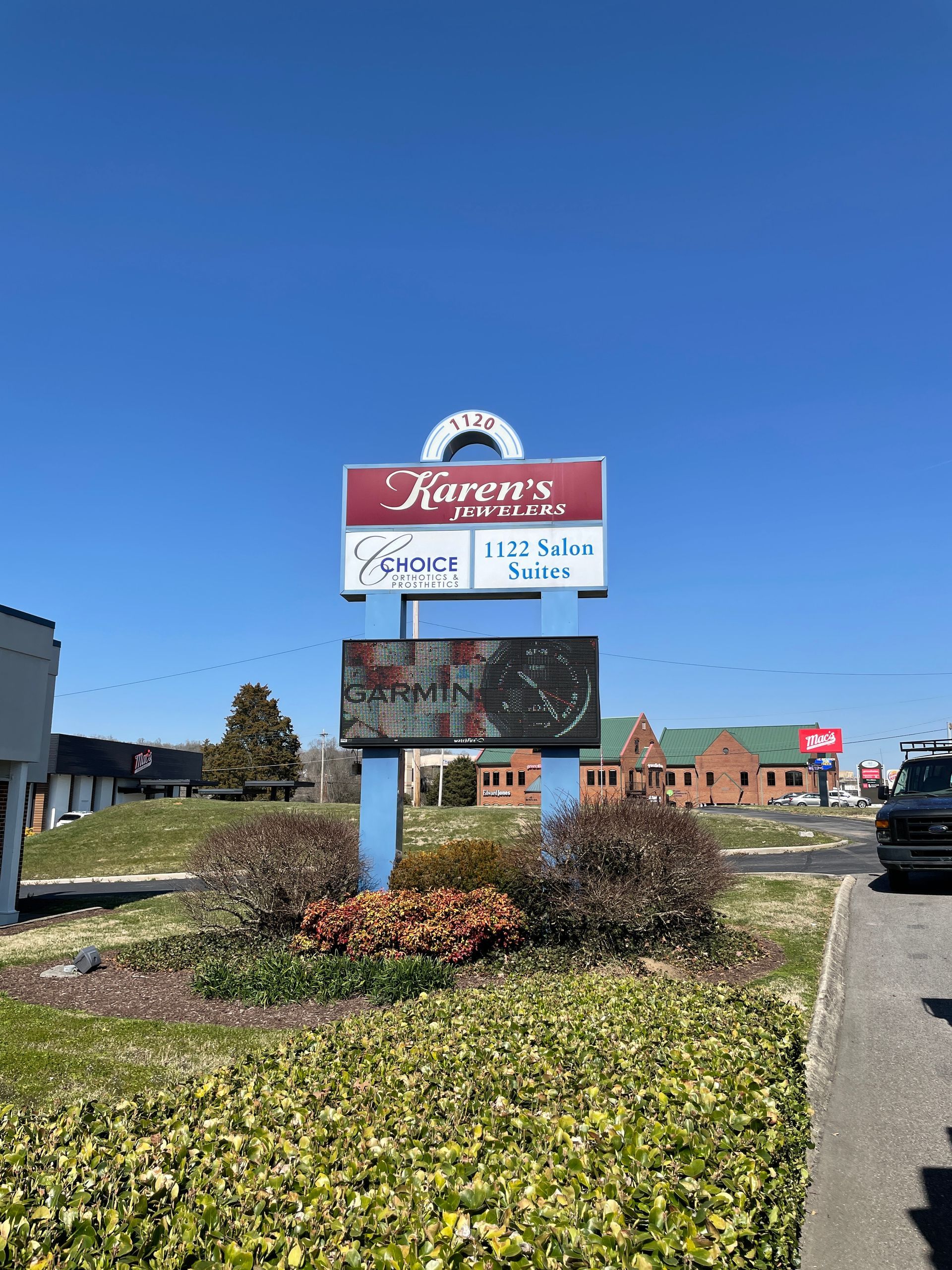Sign for Karen's Kloset, 1723 Dallas, Texas. Blue and red sign in front of bushes, sunny day.
