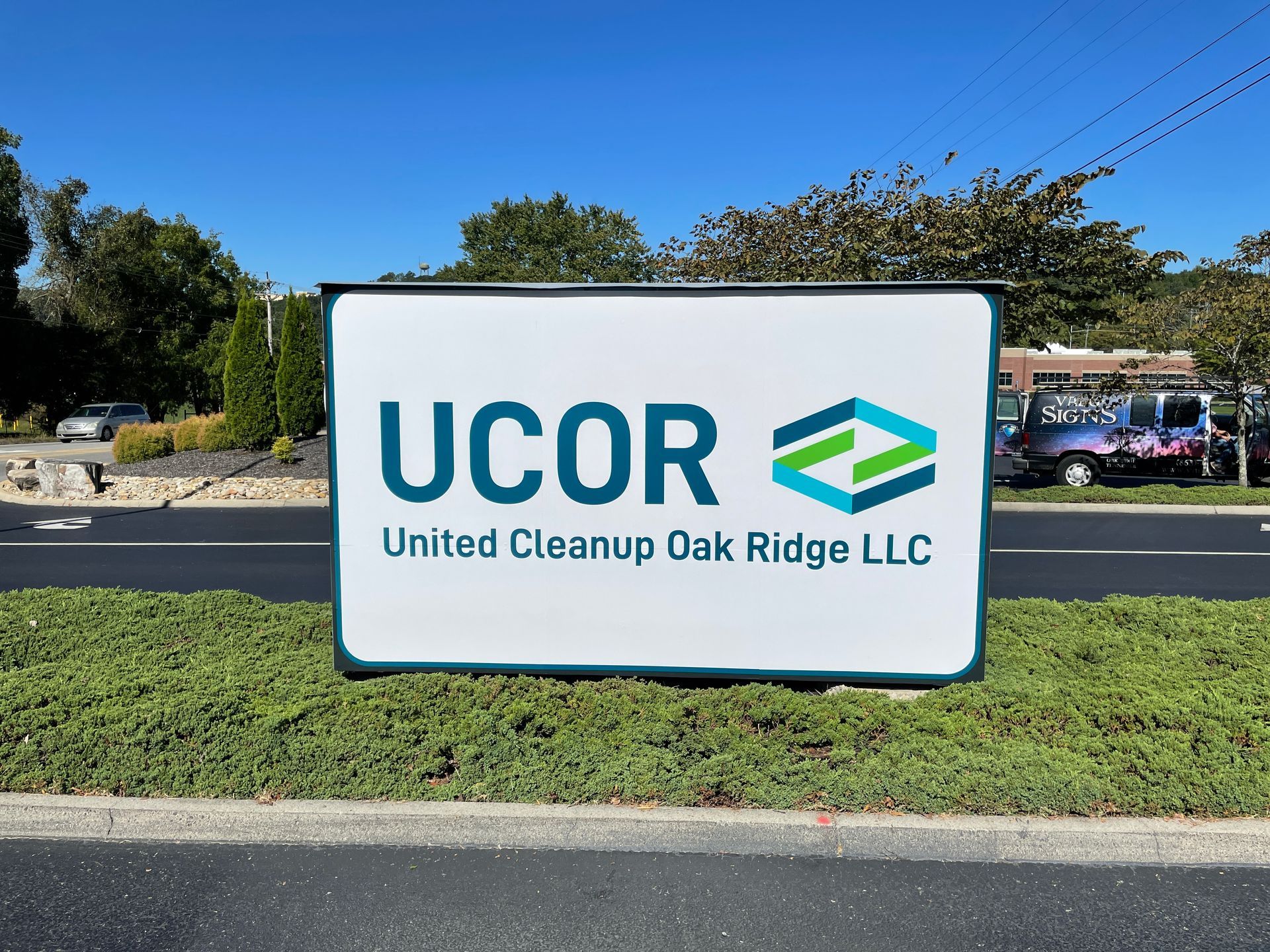 Sign for United Cleanup Oak Ridge LLC, featuring a logo with green and blue geometric shapes.