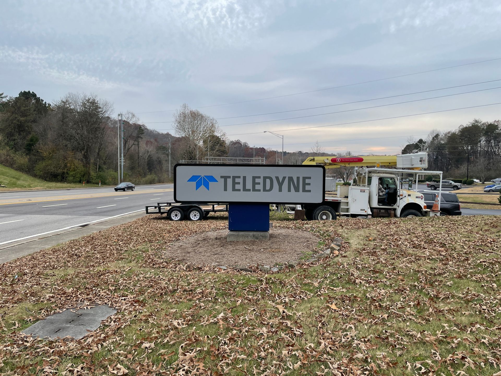 Teledyne sign by a highway, with service truck parked nearby. Overcast day.