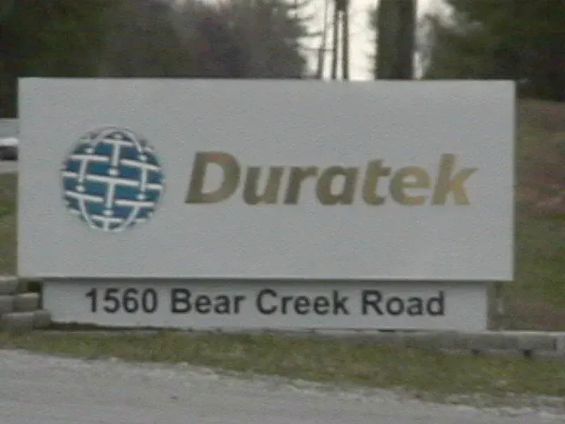 Sign for Duratek at 1560 Bear Creek Road, white with logo and gold lettering.