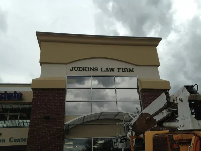 Judkins Law Firm building with tan and brick facade; cloudy sky.