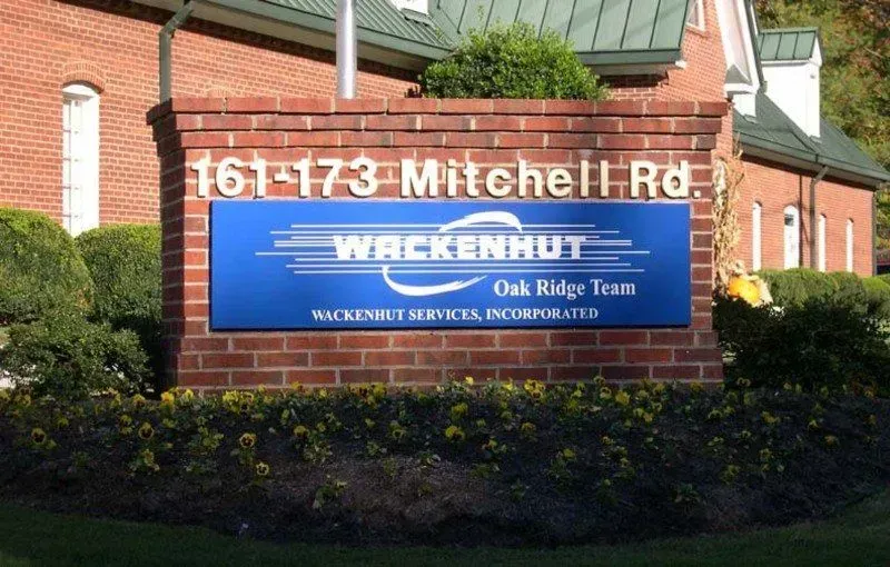 Sign for Wackenhut at 161-173 Mitchell Rd. Blue sign with white text on a brick pillar. Oak Ridge, TN.