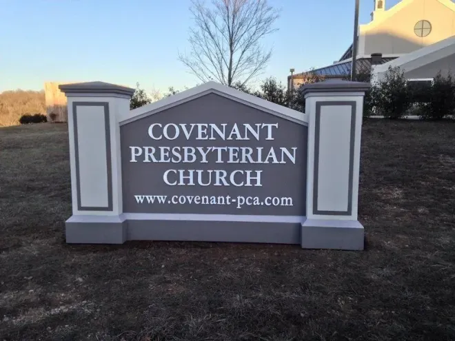 Sign for Covenant Presbyterian Church, gray and white with text, www.covenant-pca.com, on grassy lawn.