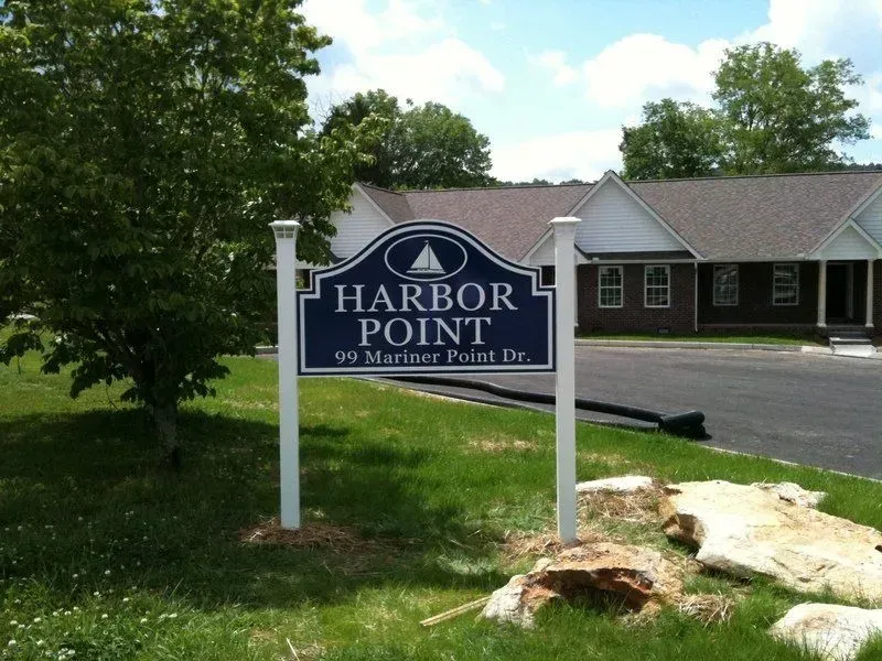 Harbor Point sign, blue and white, with address 99 Mariner Point Dr., in front of a building.