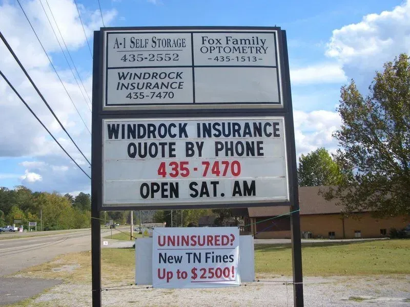 Sign with businesses: A-1 Self Storage, Fox Family Optometry, and Windrock Insurance. Text warns of uninsured TN fines up to $2500.