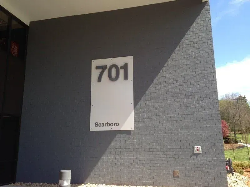 Gray building exterior with the number 701 on a white sign that reads 