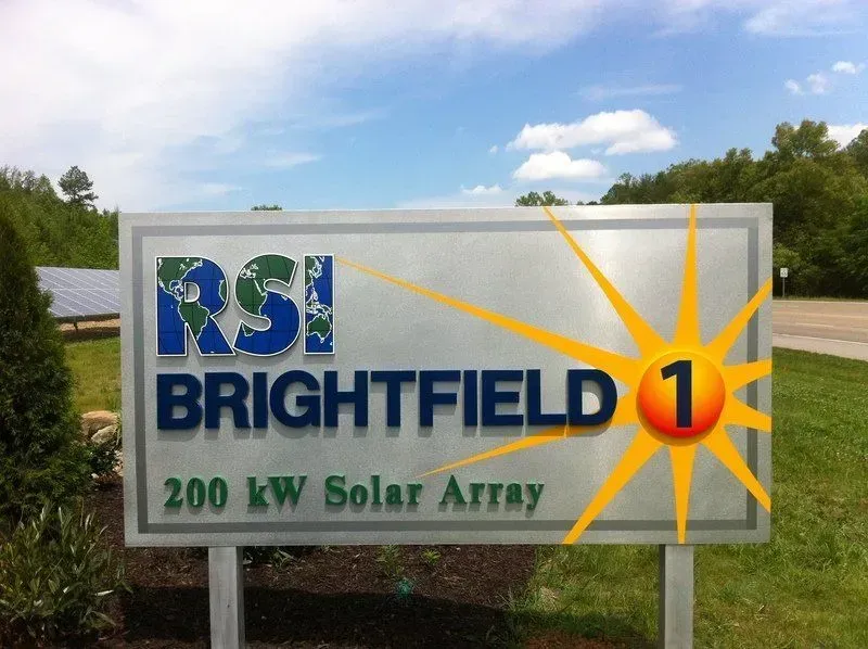 Sign for Brightfield 1, a 200 kW solar array, with logo and solar panel background.
