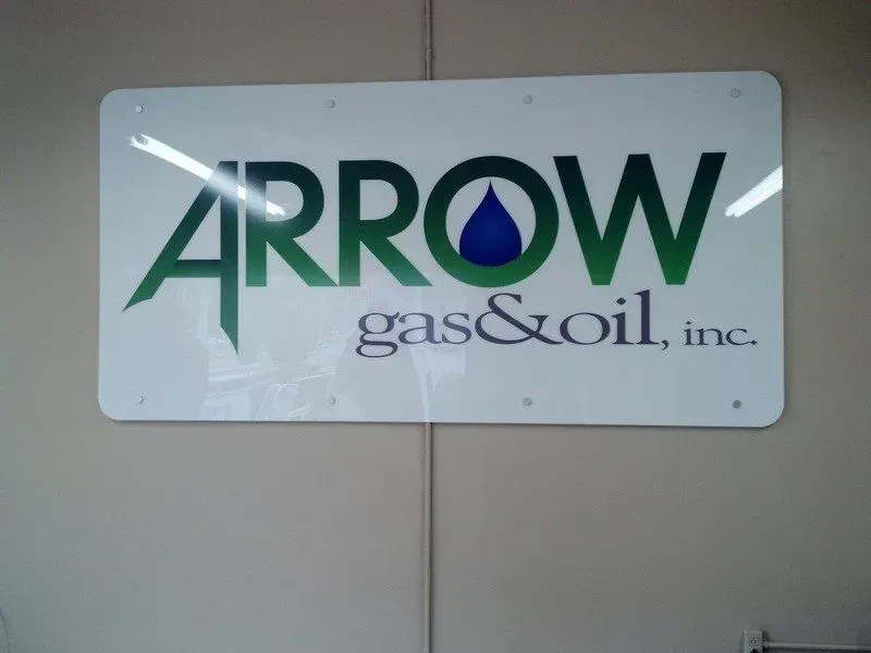 Sign for Arrow Gas & Oil, Inc. with green text and a blue water droplet icon. White background.