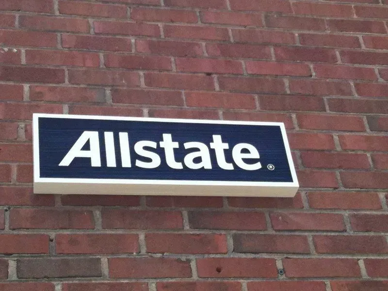 Allstate sign on a brick wall; navy blue background, white text, and a cream-colored frame.