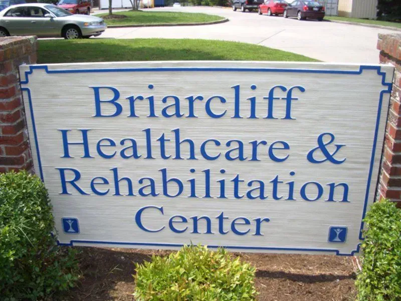 Sign for Briarcliff Healthcare & Rehabilitation Center; blue text on white background with blue border, brick base, shrubbery.