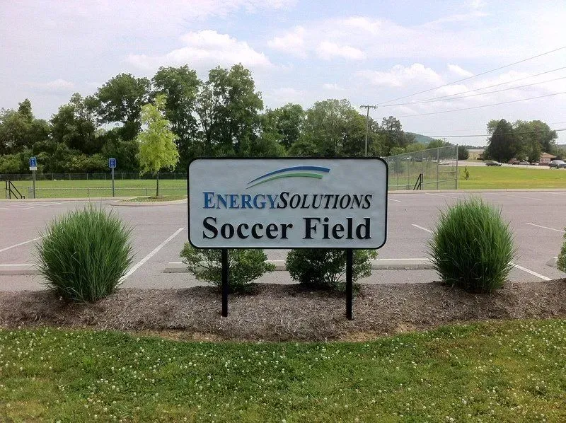 Sign for Energy Solutions Soccer Field in front of a parking lot and green field.