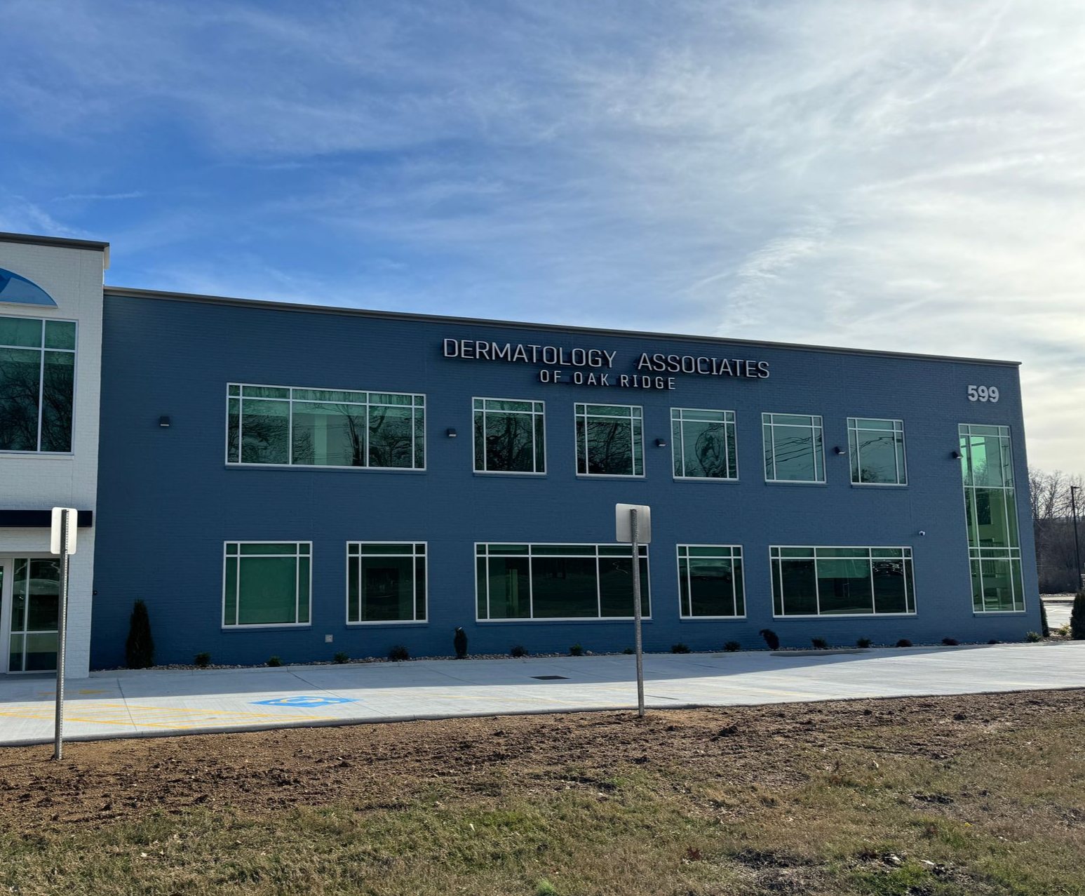 Sign for New Fairview Baptist Church in front of a cemetery, under a blue sky.