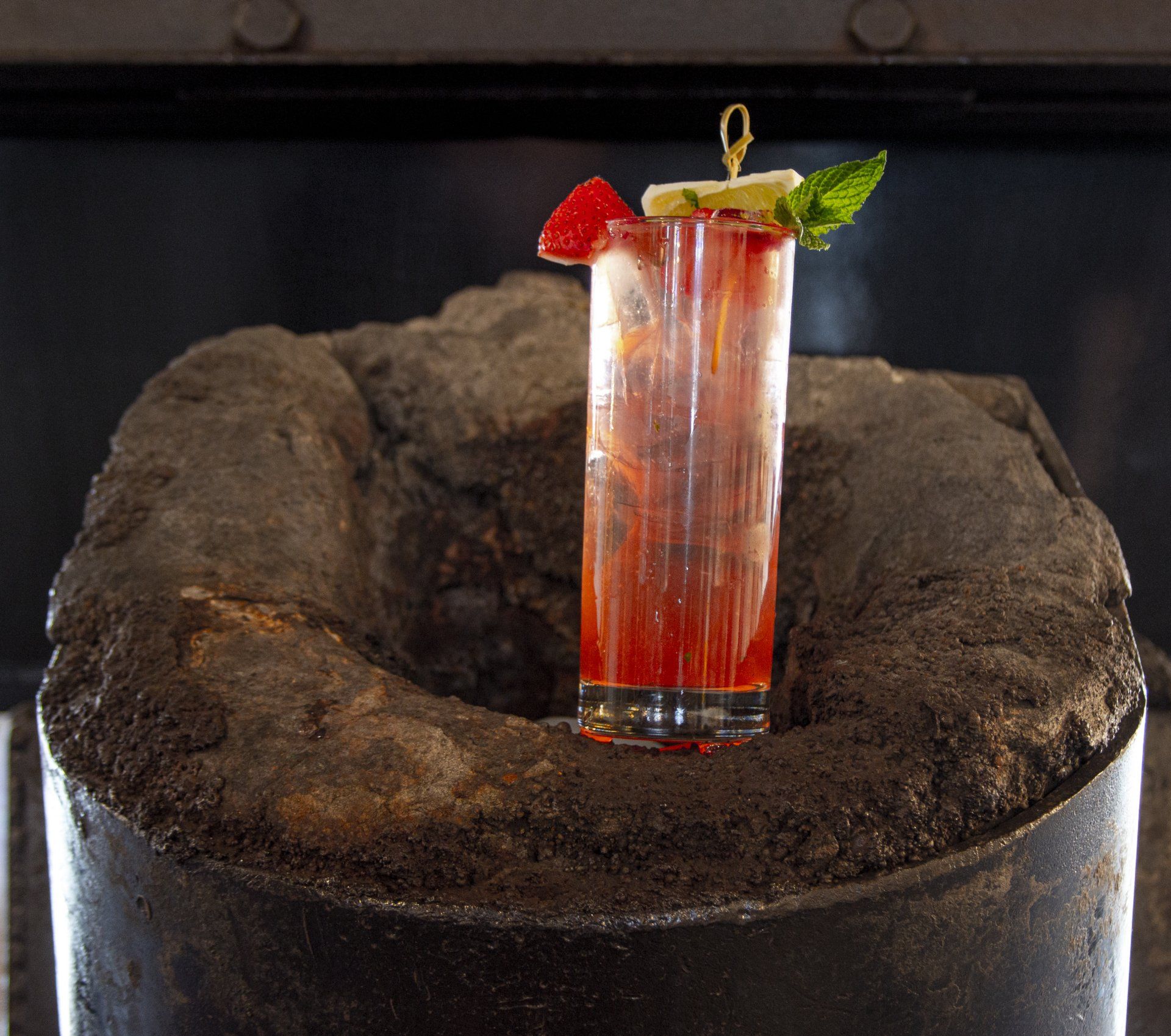 A tall glass of red liquid with a strawberry on top