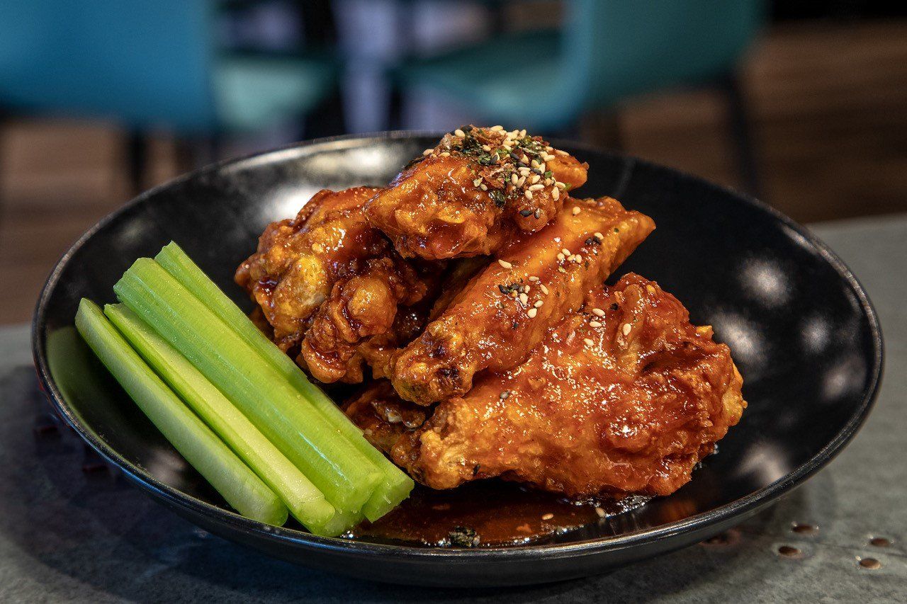 A black plate topped with chicken wings and celery sticks.