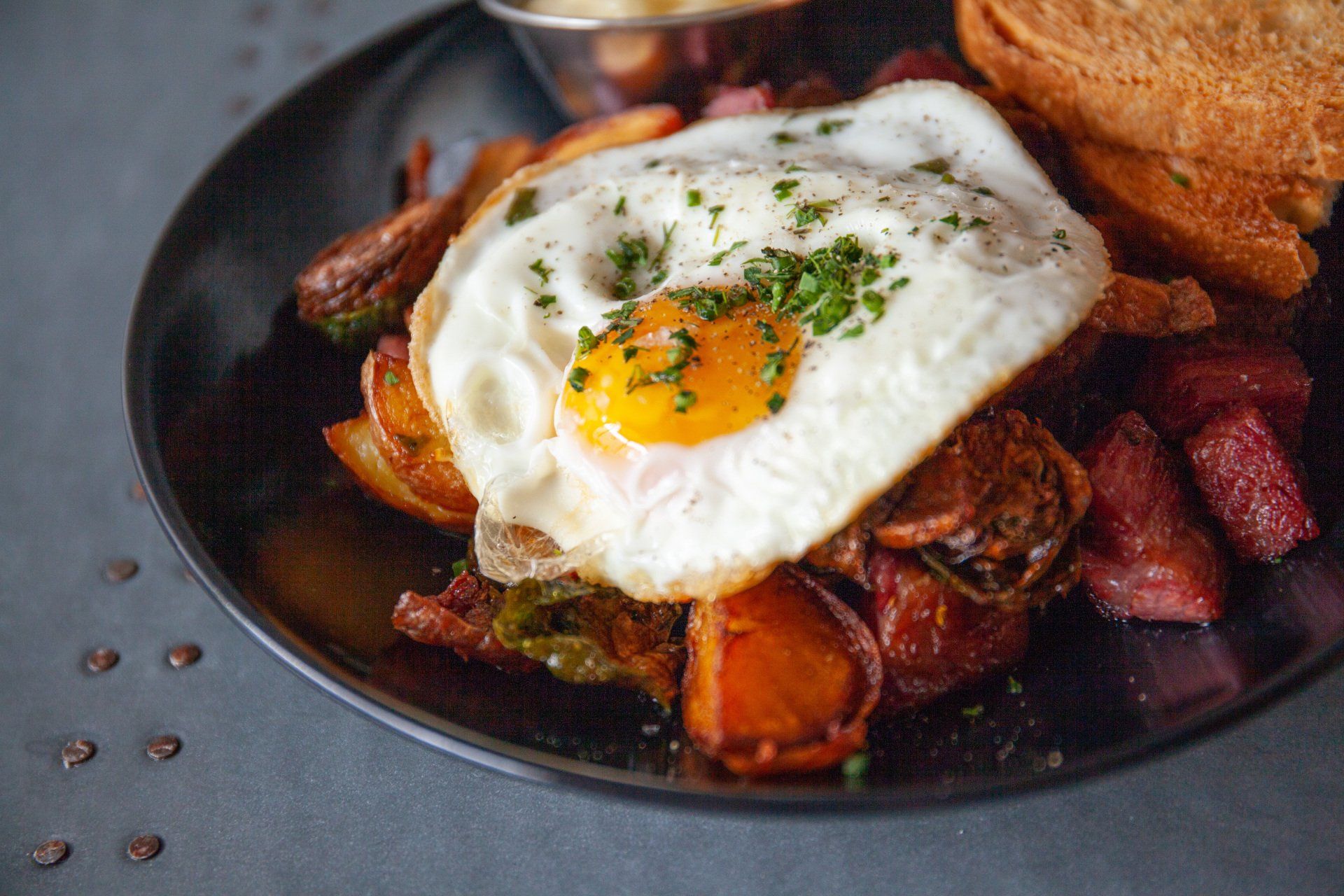 A plate of food with eggs , potatoes , and toast on a table.
