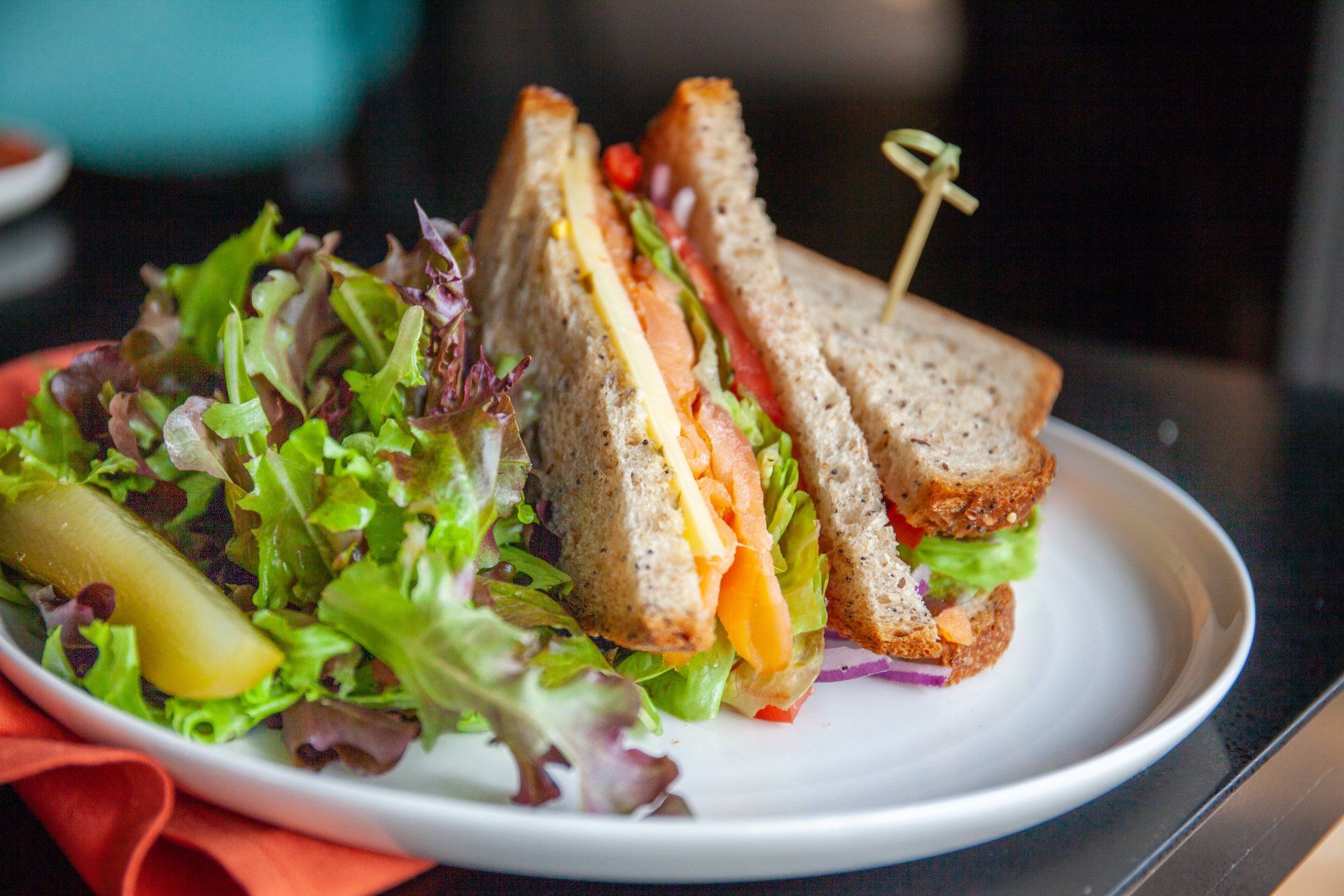 A sandwich and a salad on a white plate on a table.