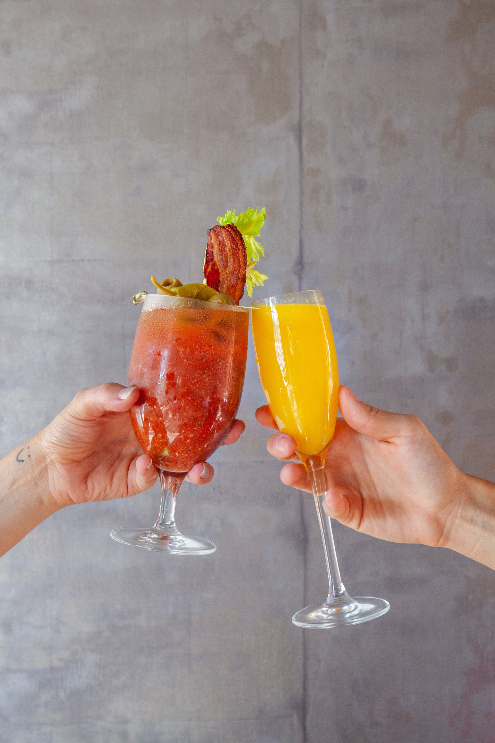 Two people are toasting with two drinks in their hands.