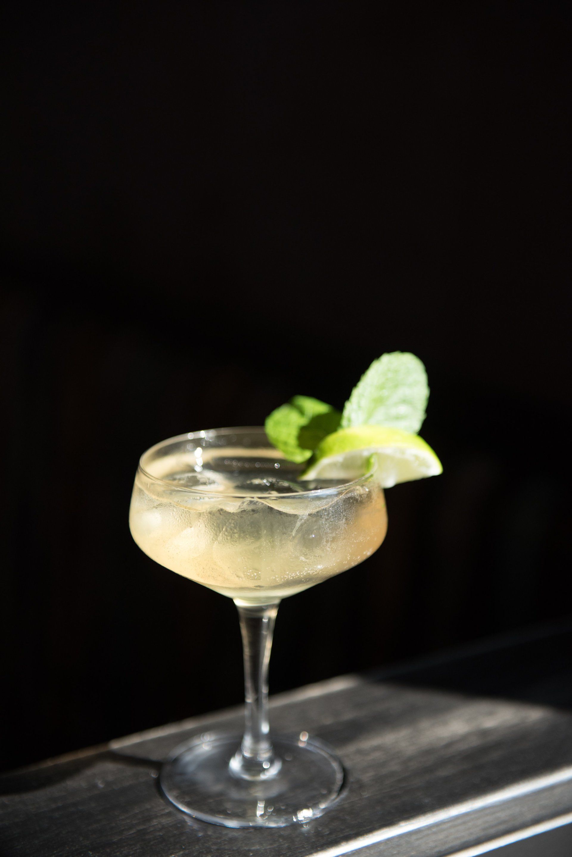 A close up of a cocktail in a coupe glass on a table.