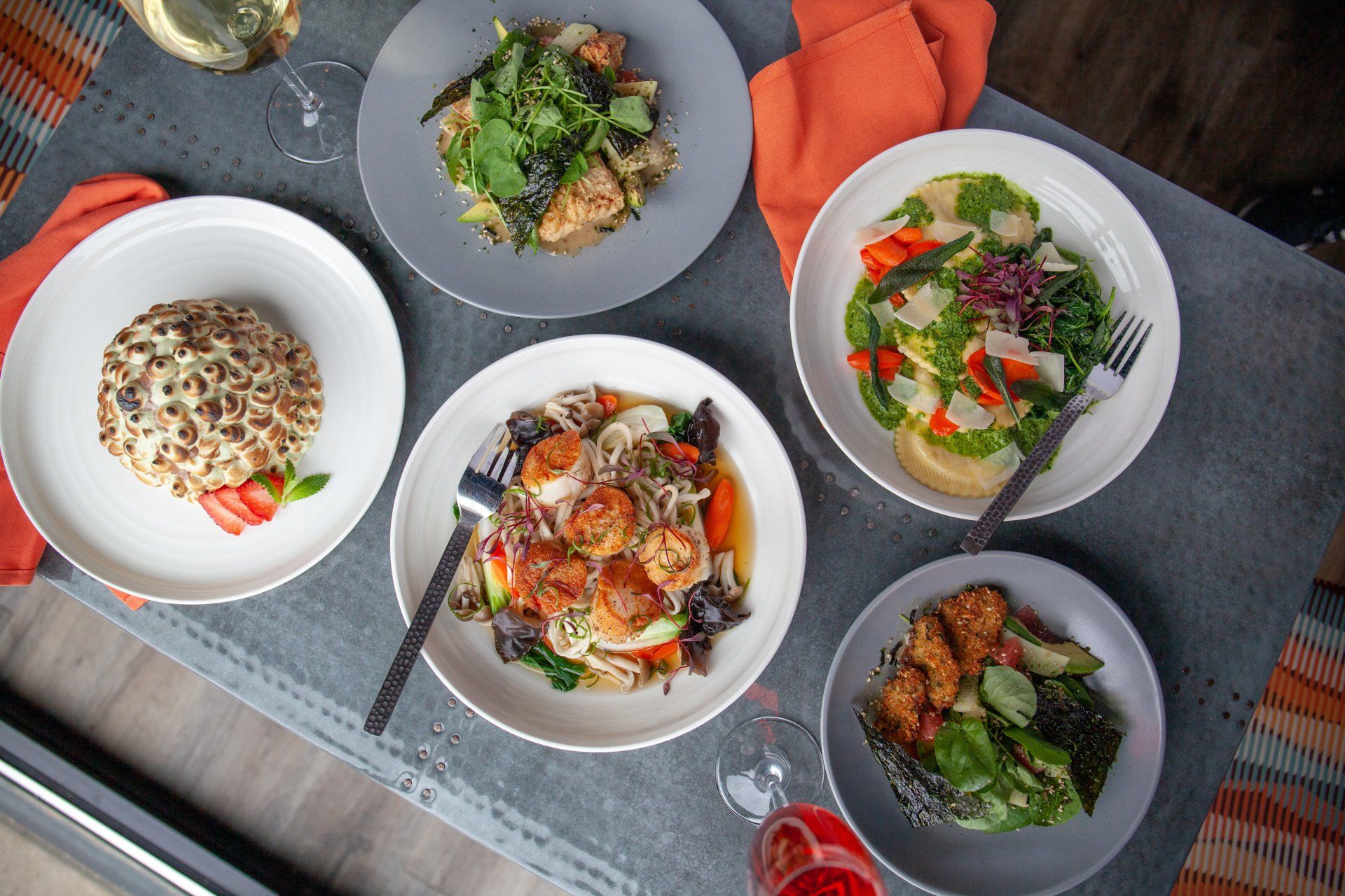 A table topped with plates of food and a glass of wine.