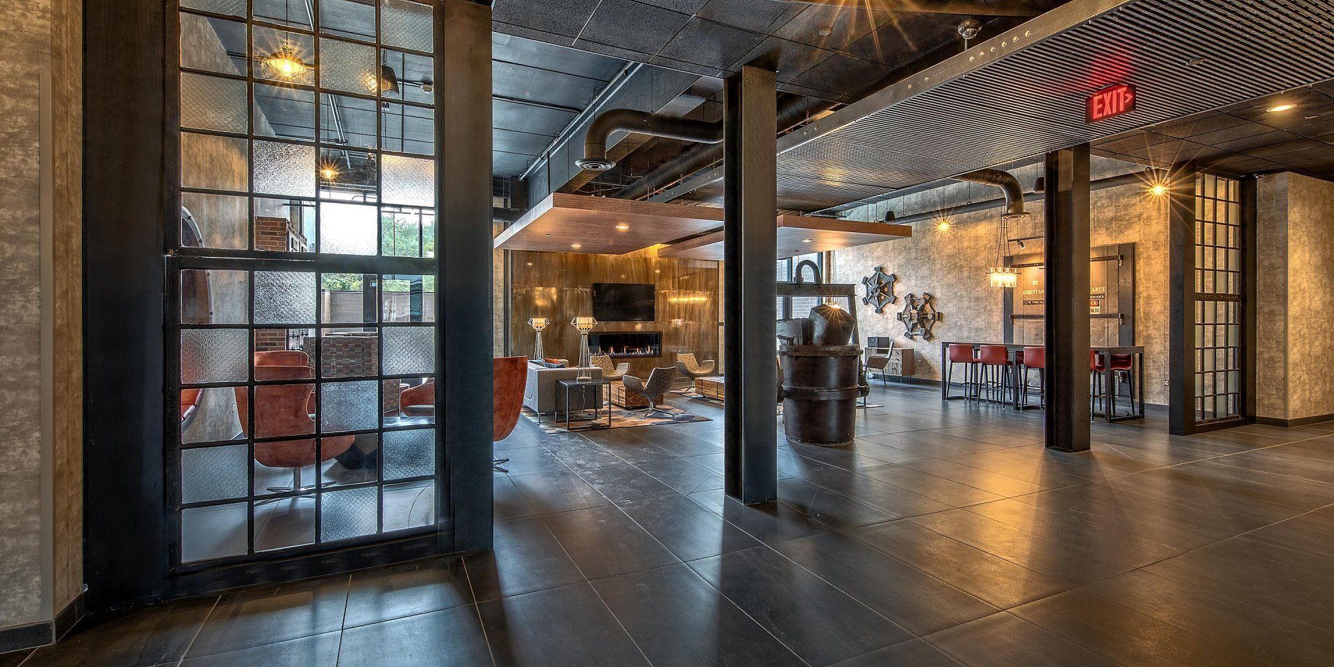 A large room with a lot of windows and a red exit sign.
