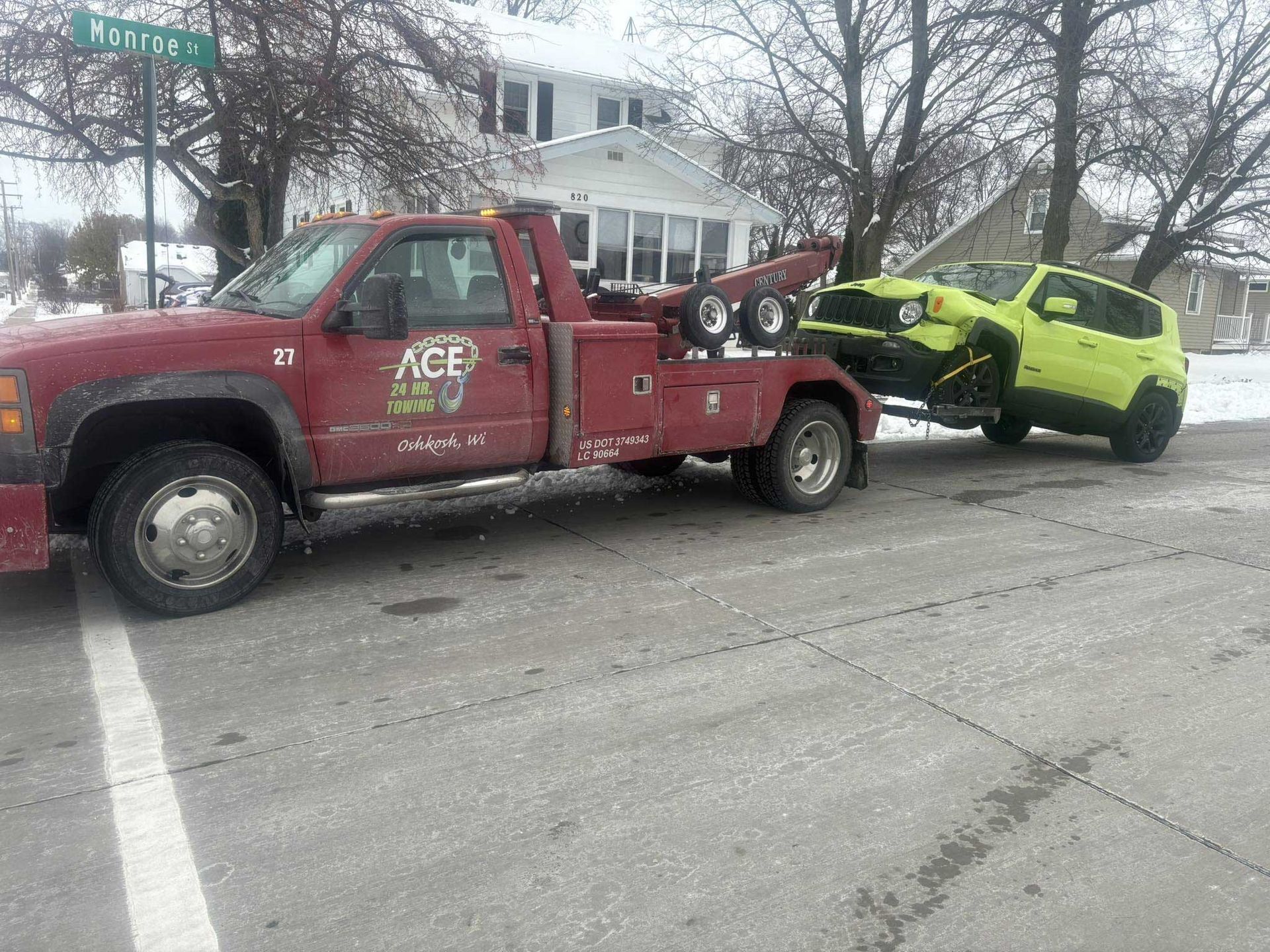 Red tow truck towing a bright yellow SUV on a snowy street.