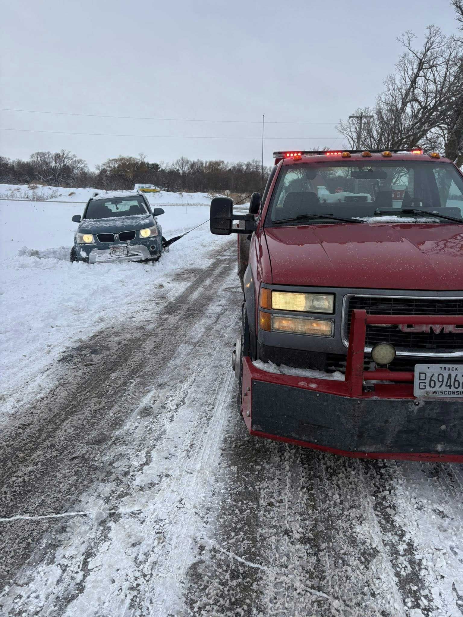 Red pickup truck and a snow-covered car on a snowy road after a winter storm