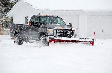 A plow truck clears a driveway