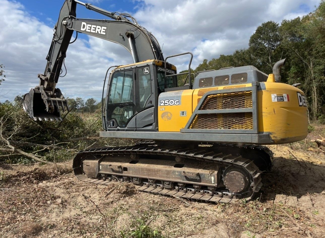 A yellow and gray excavator is parked in a dirt field.