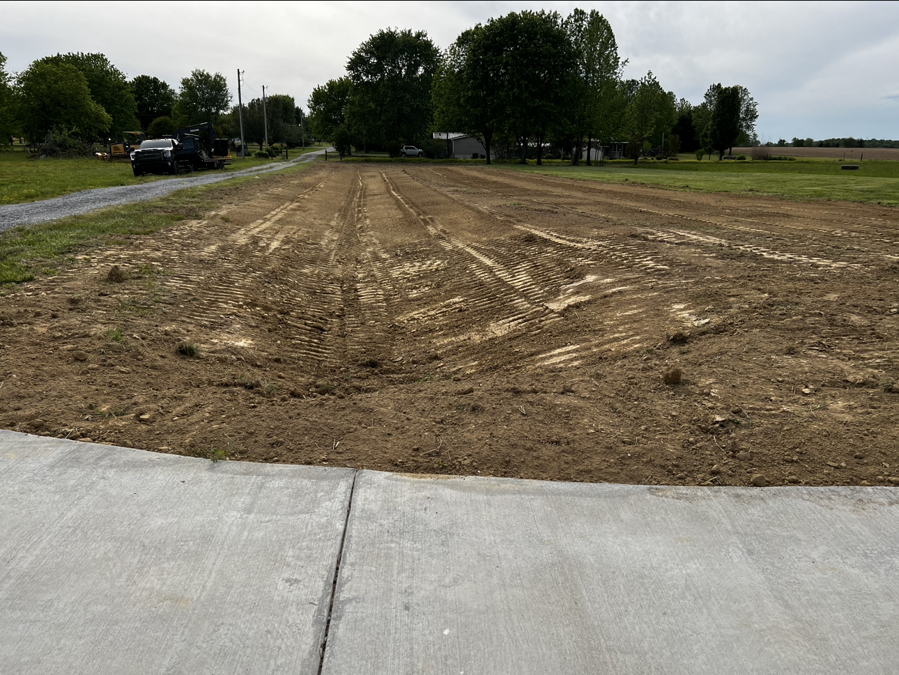 A car is parked on the side of a road next to a dirt field.