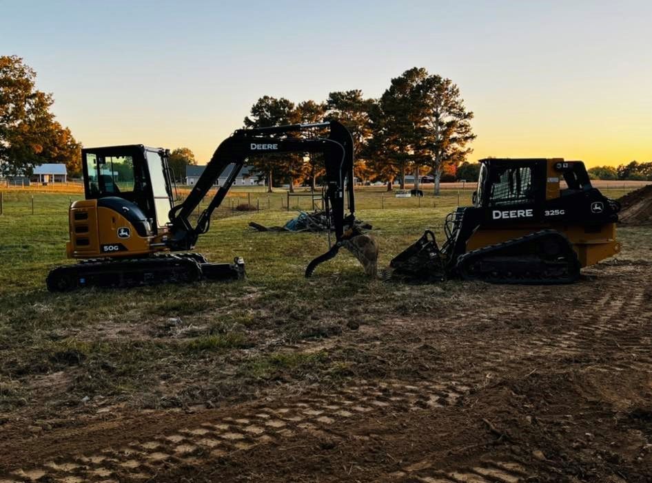 Two construction vehicles are parked in a dirt field.