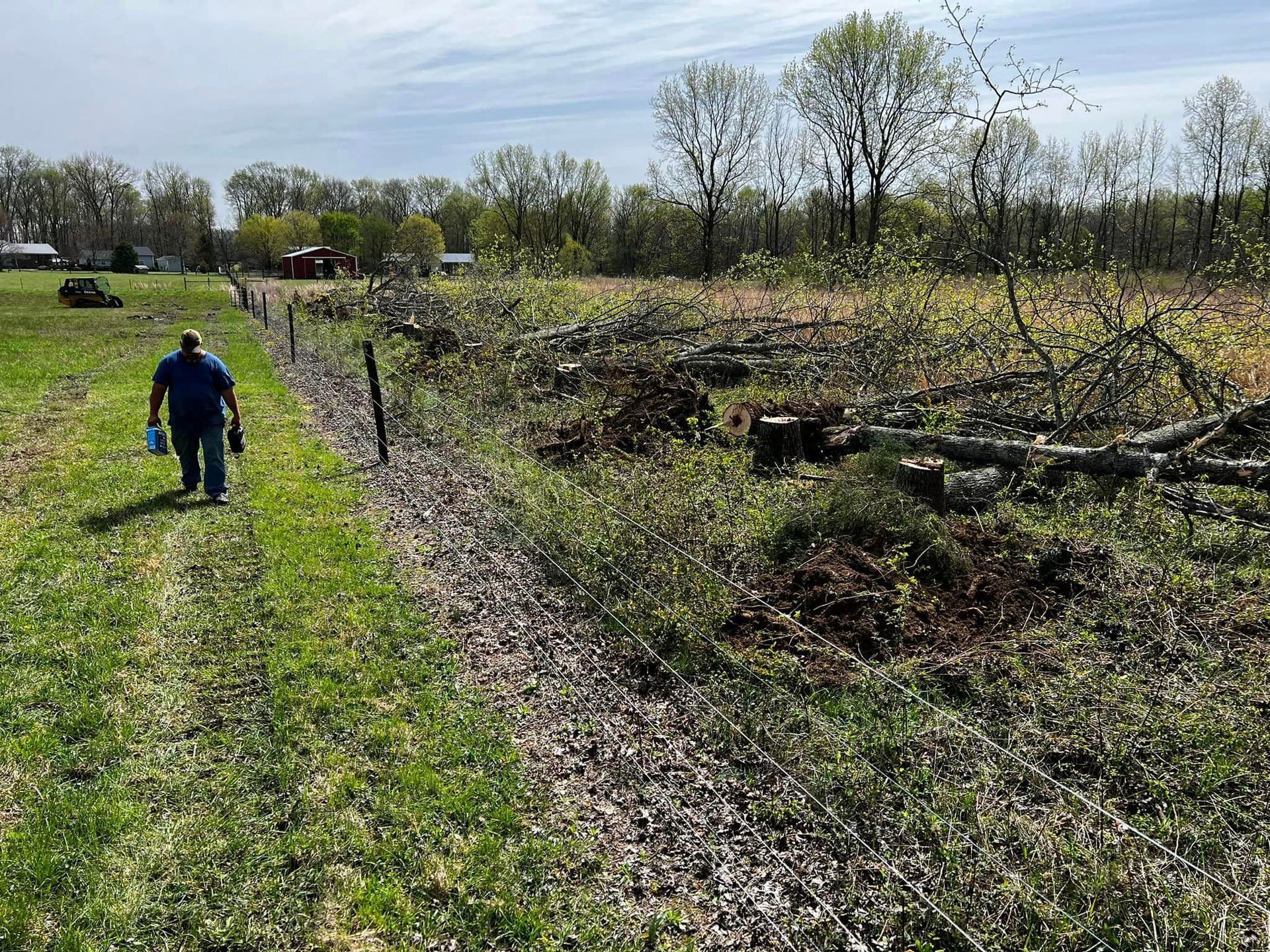 A man is walking down a dirt road in a field.
